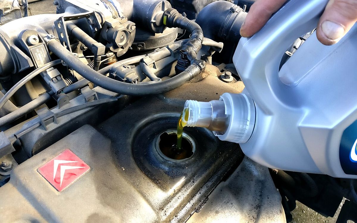 Óleo lubrificante sendo colocado no motor do carro